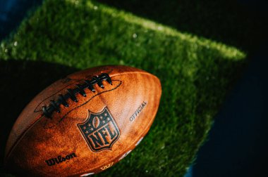 New York, ABD, 11 Eylül 2023: NFL 'in Markası: Deri Top ve İkonik Logo. Yeşil Çimen arka planda, siyah kurgu alanı, ulusal futbol ligi resmi Wilson topu