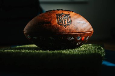 New York, ABD, 11 Eylül 2023: NFL 'in Markası: Deri Top ve İkonik Logo. Resmi Ulusal Futbol Ligi topu sporcuların soyunma odasının gölgesinde yer alıyor. Siyah düzenleme alanı