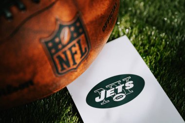 NEW YORK, USA, SEPTEMBER 11, 2023: New York Jets logo on the ground and official NFL ball on green grass. Jets card, edit space clipart