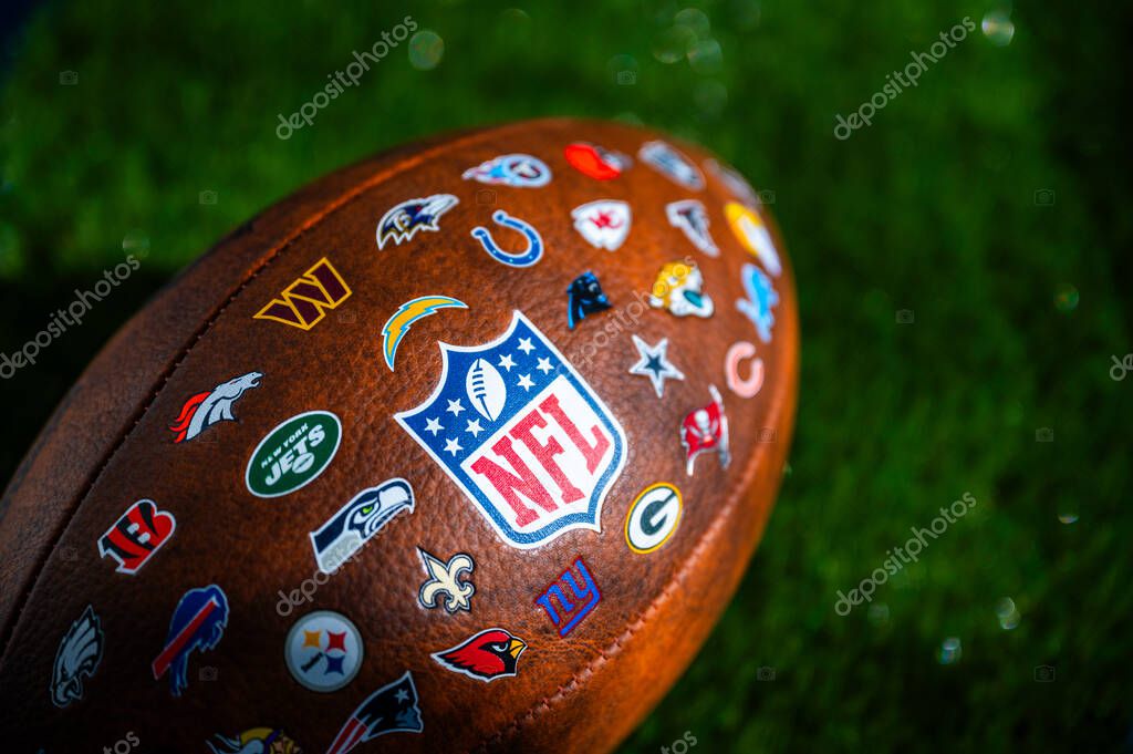 NEW YORK, USA, SEPTEMBER 11, 2023: NFL football ball, logo of national football league and logos of all teams. Green background, edit space