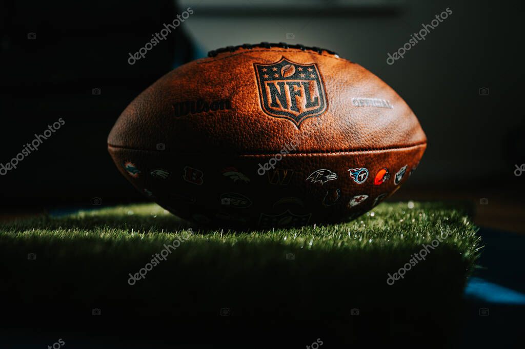 NEW YORK, USA, SEPTEMBER 11, 2023: NFL's Trademark: Leather Ball and Iconic Logo. Official National Football league ball places in shadow of athletes dressing room. Black edit space