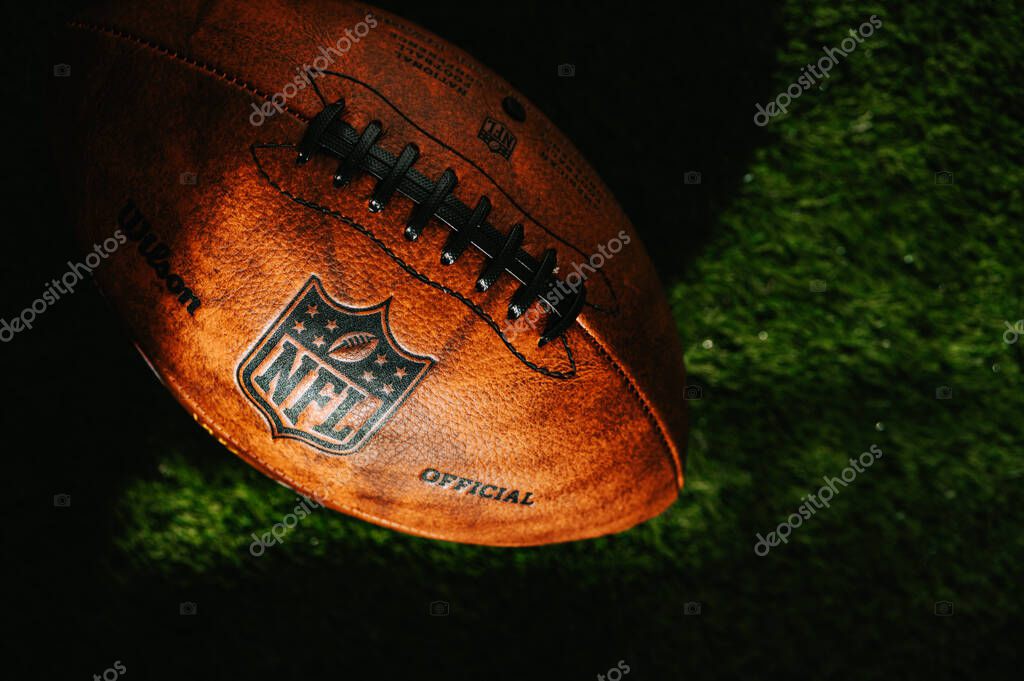 NEW YORK, USA, SEPTEMBER 11, 2023: Detailed View of the NFL Leather Ball on the green field, covered by evening light and shadow. Illustrative photo, black edit space