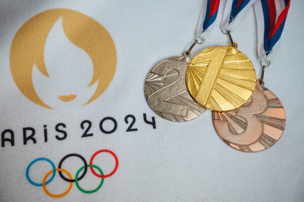 PARIS, FRANCE, JANUARY 4. 2024: Gold silver and bronze medal on white blanket with official logo of Summer olympic game in Paris 2024