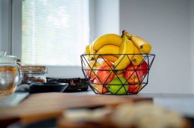 Pleasant sunlight accentuates a banana in a glass bowl on the kitchen counter clipart