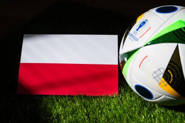 MUNICH, GERMANY, 17 Nisan 2024: Polonya ulusal bayrağı ve Almanya 'da düzenlenen Euro 2024 resmi futbol topu yeşil çimlerin üzerine yerleştirildi. Siyah arkaplan, boşluğu düzenle