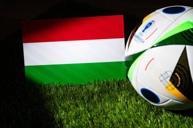 BERLİN, GERMANY, 17 Nisan 2024: Macaristan ulusal bayrağı ve resmi Euro 2024 futbol topu Almanya 'da yeşil çimlerin üzerine yerleştirildi. Siyah arkaplan, boşluğu düzenle