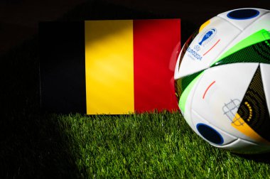 HAMBURG, Almanya, 17 Nisan 2024: Belçika ulusal bayrağı ve Almanya 'da düzenlenen Euro 2024 resmi futbol topu yeşil çimlerin üzerine yerleştirildi. Siyah arkaplan, boşluğu düzenle