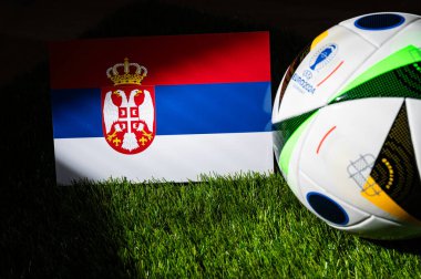 LEIPZIG, GERMANY, APRIL 17, 2024: Sırbistan ulusal bayrağı ve resmi Euro 2024 futbol topu Almanya 'da yeşil çimlerin üzerine yerleştirildi. Siyah arkaplan, boşluğu düzenle