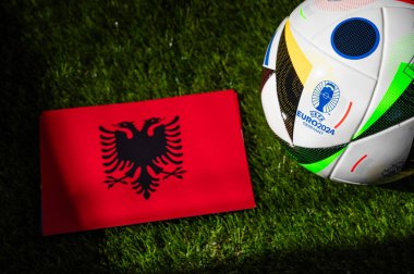 BERLİN, GERMANY, 17 Nisan 2024: Arnavutluk ulusal bayrağı ve Almanya 'da düzenlenen Euro 2024 resmi futbol topu yeşil çimlere yerleştirildi. Siyah arkaplan, boşluğu düzenle