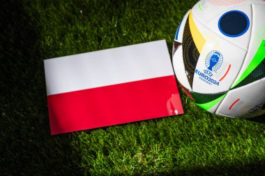 MUNICH, GERMANY, 17 Nisan 2024: Polonya ulusal bayrağı ve Almanya 'da düzenlenen Euro 2024 resmi futbol topu yeşil çimlerin üzerine yerleştirildi. Siyah arkaplan, boşluğu düzenle