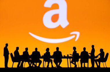 SEATTLE, ABD, 10 Ekim 2024: Amazon Finansal Büyüme Diyaloğu. Şirket toplantısındaki yöneticilerin siluetleri. Gelir tablolarını inceliyorlar. Arkalarında şirket logosu var..