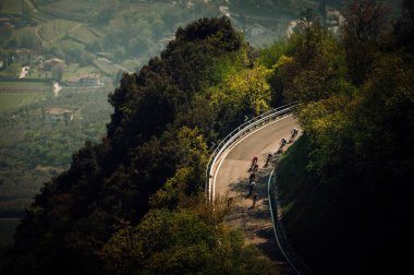 Road cyclist while professional Race in Italy. Cycling peloton from above in green forest clipart