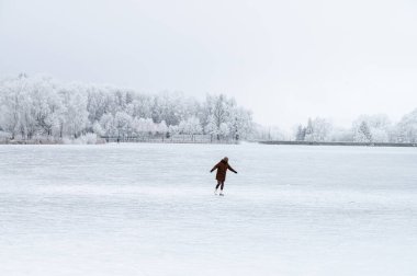 Magical white scenery glows with Christmas charm as children skate freely across the frozen pond