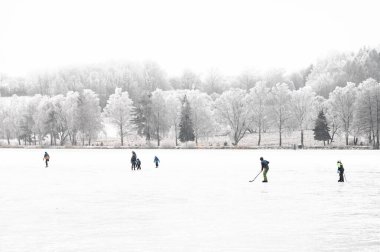 Children skating joyfully across a frozen pond, surrounded by a white frozen Christmas landscape filled with magic and peace