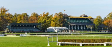 Wroclaw, engelli at yarışı pisti ve taraftarlar için yüksek tribünler, güneşli bir günde renkli ağaçlı sonbahar manzarası.