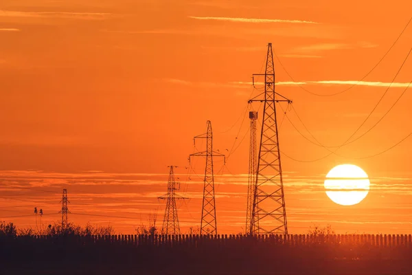 Maszty Linii Energetycznej Podczas Pomarańczowego Zachodu Słońca Okrągły Dysk Słoneczny — Zdjęcie stockowe