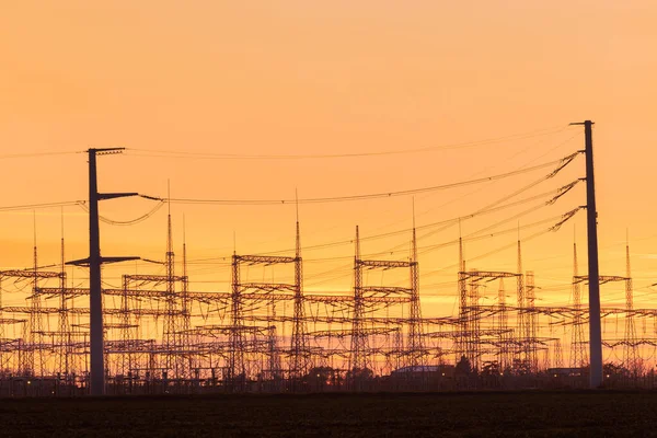 Duża Elektrownia Masztami Linii Elektroenergetycznych Pomarańczowe Niebo Zachodzie Słońca — Zdjęcie stockowe