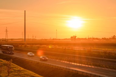 Otobandan geçen arabalar, otoyolda turuncu gün batımı..