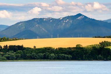 Besenova köyünden dağ manzarası, alçak Tatras Ulusal Parkı 'ndaki yüksek dağ zirveleri manzarası. Vah nehri kıyısındaki yapay su deposunun manzarası.