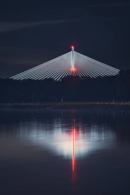 Wroclaw, Redzinski Köprüsü geceleri aydınlatılır. Yapı, Odra Nehri 'nin kıyısındaki ağaçların üzerinden yükselir..