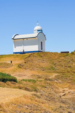 Macquarie Limanı Deniz feneri, uçurumun tepesinde beyaz deniz feneri güneşli bir yaz gününde deniz manzarası.