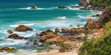 Sahilde volkanik kayalar olan Avustralya kıyıları, deniz kenarındaki kayalıklardan mavi sularla manzarayı seyrediyor..