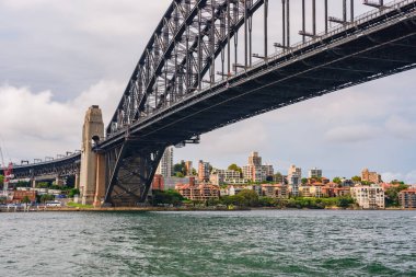 Sydney, Avustralya - 03 Mart 2023: Sydney Limanı Köprüsü, nehir kıyısındaki kentsel binalar, nehir kenarındaki feribottan manzara.