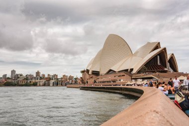 Sydney, Avustralya - 3 Mart 2023: Sydney Opera Binası, yürüme yolundan Opera binasına ve nehrin diğer kıyısındaki Mattawunga bölgesine doğru bakın..