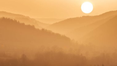 Eastern Sudetes, orange sunset over the mountains with a foggy valley, mountain landscape in the evening with a sun disk. clipart