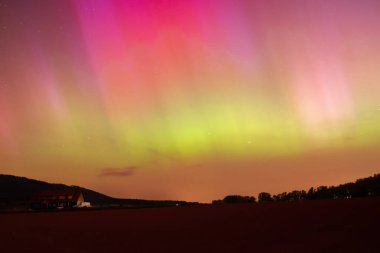 Polonya 'da Aurora Borealis, gece gökyüzünde renkli bir gösteri, dağ manzarasında bir ışık fenomeni.