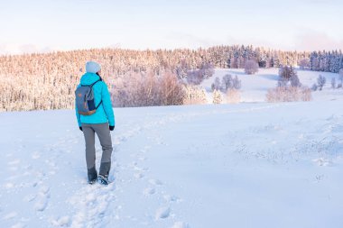 Doğu Sudetes, dağda karla kaplı bir patikada, beyaz karda yürüyüş yapan ve karla kaplı tepeleri gören genç bir kadın, dağlardaki kış manzarası..