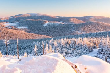 Eastern Sudetes, View of snowy mountain range from hiking trail during winter hike in the mountains, viewpoint of wide winter landscape in the mountains at sunset. clipart