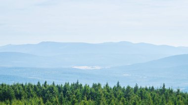 Dev Dağlar, yeşil ormanın arkasındaki sıradağların manzarası, aydınlık bir yaz gününde dağ manzarası..