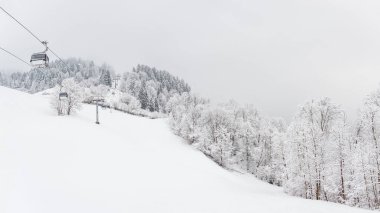 Karlı ağaçlar ve dağın tepesine giden bir gondol demiryolu olan kış manzarası dağ yürüyüşü sırasında dağ yürüyüşü manzarası. Bulutlu ve sisli bir kış günü.