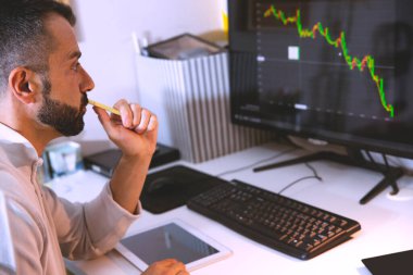 Man 'in finansal danışmanlık işi için evden yakın çekim. Erkek, kulaklık takıyor ve bitcoin grafiğiyle bilgisayar monitörü arıyor. Çevrimiçi yatırım platformlarında Olgun İşadamı