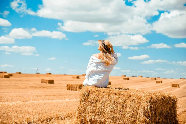 stock image Woman farmer on Dry rectangle golden color haystack on the big farmland. Beautiful Female enjoying after harvest on the Field with straw stack of wheat and blue sky. Copy space