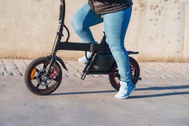 E- scooterlı İspanyol kadın banliyö yolcusu, şehirde geziniyor.