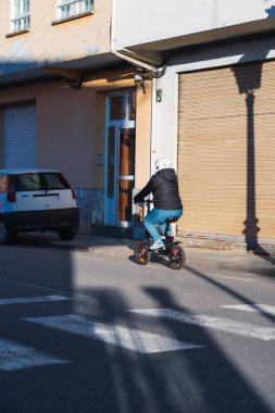 Hispanic female commuter on e-scooter, cruising a city block