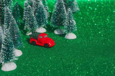 Kırmızı retro oyuncak araba, Noel ağacının arka planında küçük bir Noel ağacı taşıyan kamyon. Noel kartları. Kamyon. Teslimat servisi.