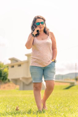 Telefonda konuşan bir kadın ve arka planda bir ormanda park etmiş bir karavanın macera gezisi görüntüsü. kullanılabilir alanı kopyala