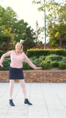 Caddedeki parkta Charleston dansı yapan olgun bir kadın..