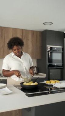 Kübalı genç bir kadın tavada patates püresi kızartıyor ve Küba usulü doldurulmuş patatesleri hazırlamak için konuşuyor..