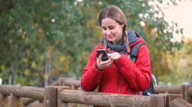 Genç bayan yürüyüşçü akıllı telefona danışıyor ve yürürken fotoğraf çekiyor..