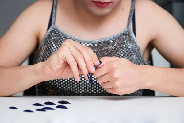 Young unrecognizable gender fluid person removing glitter false nails.