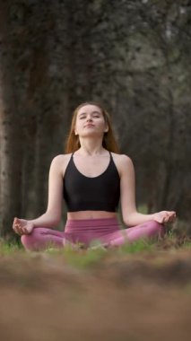Kızıl saçlı genç kadın ormanda meditasyon yapıyor. Doğada meditasyon.