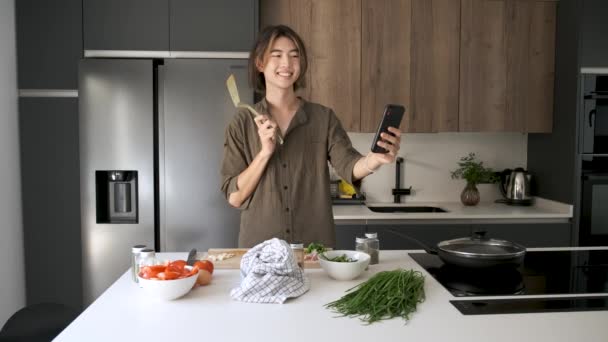 Uśmiechnięty Azji Młody Człowiek Biorąc Selfie Podczas Gotowania Kuchnia — Wideo stockowe