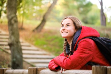 Gülümseyen genç bayan yürüyüşçü ormanda manzarayı seyrediyor..