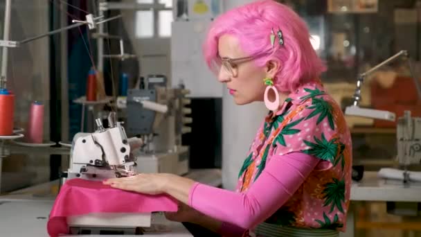 Kleermaker Met Roze Haar Kleurrijke Kleding Aan Het Werk Een — Stockvideo