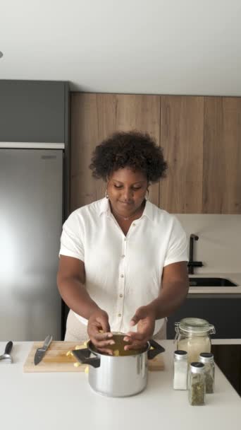 笑容可亲的年轻古巴女人把切好的生土豆放进锅里煮 — 图库视频影像