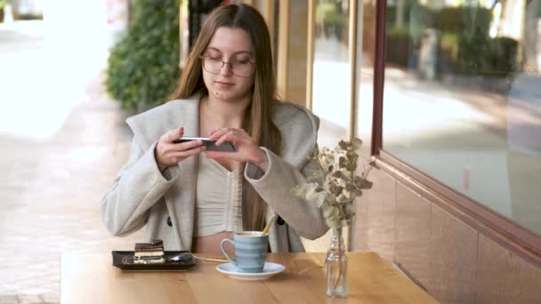 カフェで食べる前にスマホでケーキの写真を撮る若い女性 — ストック動画